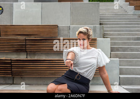 Portrait de l'un certain cheveux courts Caucasian business femme en blouse blanche jupe noire présentant un jardin extérieur. Copie vide de l'espace pour le texte. Banque D'Images