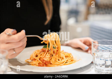 Close-up spaghetti Bolognese enrouler autour de la fourchette. Fromage Parmesan. Jeune femme mange des pâtes italiennes avec de la tomate, de la viande. Banque D'Images