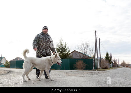 Un homme en salopette pour une promenade avec un chien Banque D'Images