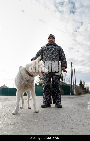 Un homme en salopette pour une promenade avec un chien Banque D'Images