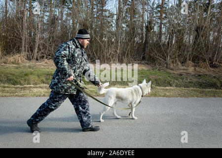 Un homme en salopette pour une promenade avec un chien Banque D'Images