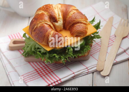 Des petits croissants sandwich pour petit déjeuner rapide avec le fromage cheddar, le concombre, et la laitue. Servi sur la petite planche à découper en bois avec fourchette et k Banque D'Images