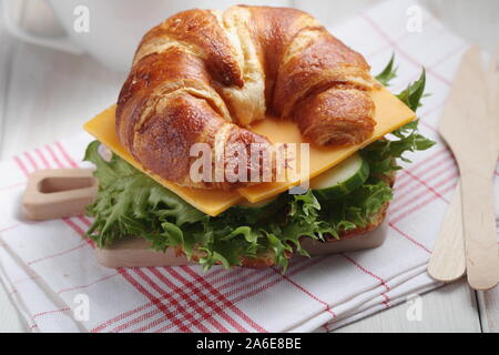 Des petits croissants sandwich pour petit déjeuner rapide avec le fromage cheddar, le concombre, et la laitue. Servi sur la petite planche à découper en bois avec fourchette et k Banque D'Images