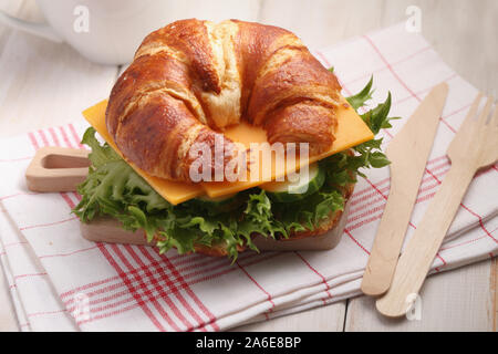 Des petits croissants sandwich pour petit déjeuner rapide avec le fromage cheddar, le concombre, et la laitue. Servi sur la petite planche à découper en bois avec fourchette et k Banque D'Images