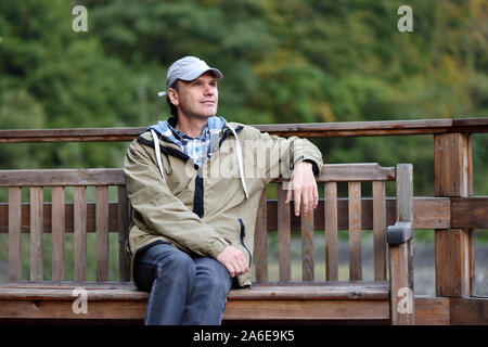 L'homme dans des vêtements décontractés assis sur un banc Banque D'Images