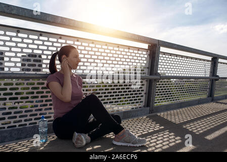 L'exercice avec le coucher du soleil, belle femme sport. Remise en forme, entraînement jogging femme concept de bien-être. Coureuse à écouter de la musique en faisant du jogging Banque D'Images