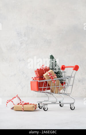 Panier plein de cadeaux divers et un arbre de Noël sur fond gris clair. Vente de Noël concept.