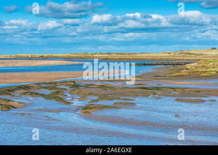 Vue sur les vasières à marée basse depuis le sentier national de la côte Norfolk, près de Burnham Overy Staithe, de l'île Scolt Head à l'arrière, East Anglia, Angleterre, Royaume-Uni. Banque D'Images