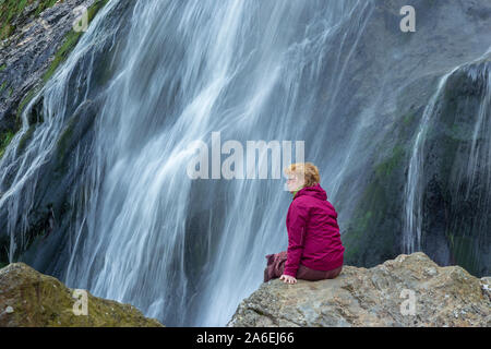 Une femme est assise en face de Powerscourt Waterfall dans le comté de Wicklow, en Irlande. Banque D'Images