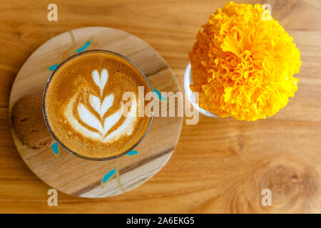 Tasse de café piccolo dans un support en bois sur table en bois dans un café. Fleurs de souci dans un verre. Vue d'en haut. Avec l'espace. Banque D'Images