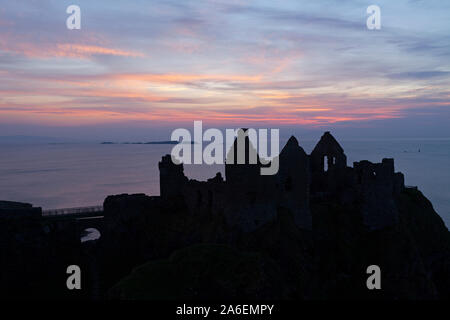 Coucher de soleil au château de Dunluce dans le comté d'Antrim, en Irlande du Nord. Banque D'Images