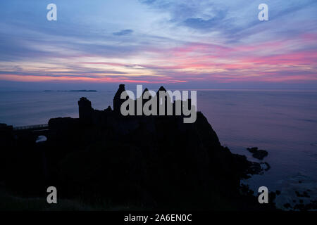 Coucher de soleil au château de Dunluce dans le comté d'Antrim, en Irlande du Nord. Banque D'Images