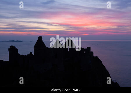 Coucher de soleil au château de Dunluce dans le comté d'Antrim, en Irlande du Nord. Banque D'Images