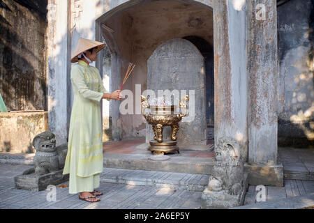 Femme portant robe traditionnelle vietnamienne et chapeau conique à un temple dans la province de Bac Ninh, Vietnam Banque D'Images