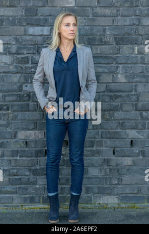 Longueur totale d'un coup d'âge moyen attrayant fit woman avec de longs cheveux blonds à l'écart tout en portant des jeans slim cool, T-shirt et des bottes avec un Banque D'Images