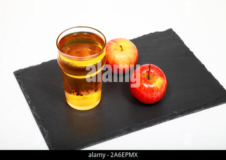 Verre de cidre de pomme sur une assiette en ardoise isolé sur fond blanc Banque D'Images