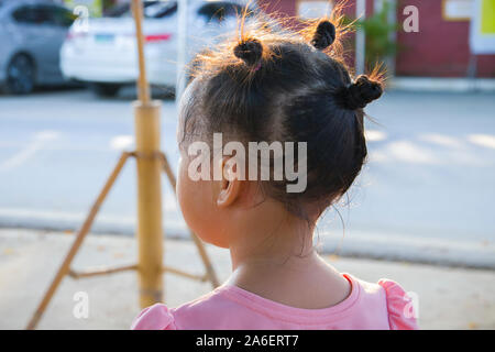 Vue arrière de la petite fille assise sur le sol et en haut. Banque D'Images