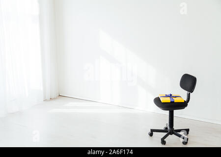 Chaise de bureau noir avec un cadeau dans un bureau blanc Banque D'Images