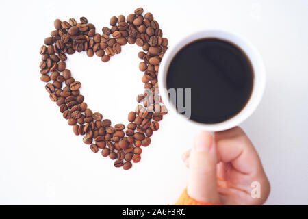 Forme de coeur fait avec des grains de café avec une tasse de café sur fond blanc. J'aime le café Banque D'Images
