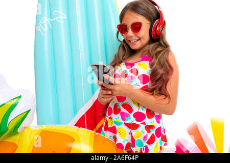 Cool girl with long hair crucifié dans des lunettes de soleil et maillot de bain se trouve près de matelas gonflables et de discuter avec ses amis et sourit Banque D'Images