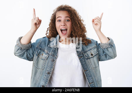 Emotive animé excité dodues mignonnes femme aux cheveux bouclés à crier à haute voix ravis de vous dire cool impressionnant promo vente pointant vers le haut, l'index anciennes Banque D'Images