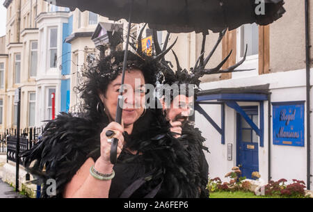 Couple en costumes traditionnels Goth marche dans la pluie, Whitby Goth Week-end Festival, Whitby, North Yorkshire, UK, 26 Octobre 2019 Banque D'Images