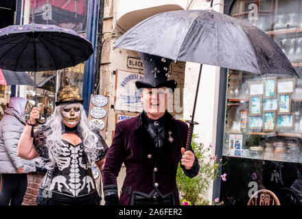 Jolly couple dans des costumes traditionnels Goth marche dans la pluie, Whitby Goth Week-end Festival, Whitby, North Yorkshire, UK, 26 Octobre 2019 Banque D'Images