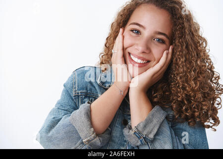 Close-up offre heureux heureux heureux aux cheveux bouclés charmant petite amie chubby sentiment optimiste de toucher les joues rougissant avec joie sentiment tête inclinable Banque D'Images