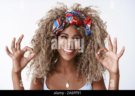 Close-up satisfaits et heureux, blonde aux cheveux bouclés coiffure afro girl, Nez Percé, serre-tête élégant, souriant, montrent bien, geste ok Banque D'Images