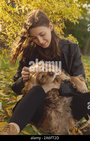 Femme avec cocker américain joue à autumn park Banque D'Images