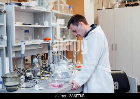 Homme scientifique effectue des expériences chimiques avec des liquides dans la science lab Banque D'Images