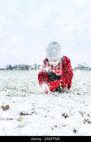 Une belle petite fille jouant dans la neige lourde chute, faisant de boules de neige, neige à Noël, Noël Banque D'Images