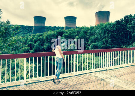 Un joli slim femmes se tenant debout sur un pont à regarder l'Ironbridge Coal power station dans le Shropshire, fermé, a condamné Banque D'Images