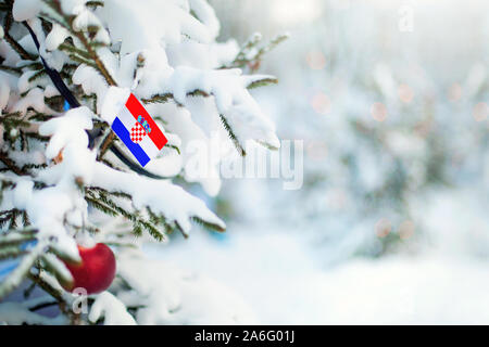 La Croatie de Noël. Arbre de Noël couvert de neige, des décorations et un drapeau de la Croatie. Contexte La forêt enneigée en hiver. Carte de vœux de Noël. Banque D'Images