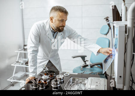 Oto-rhino-laryngologiste senior travaillant dans ENT, l'examen de TC photo office de tête du patient les caries Banque D'Images