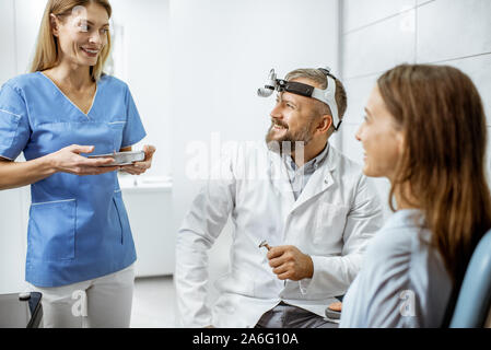 Patient avec hauts et oto-rhino-laryngologiste assistante en ORL bureau au cours de l'examen médical, le médecin de prendre des outils médicaux joyeux Banque D'Images