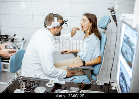Avec des patients pour l'ORL oto-rhino-laryngologiste bureau au cours de l'examen médical, le médecin examinant la gorge Banque D'Images