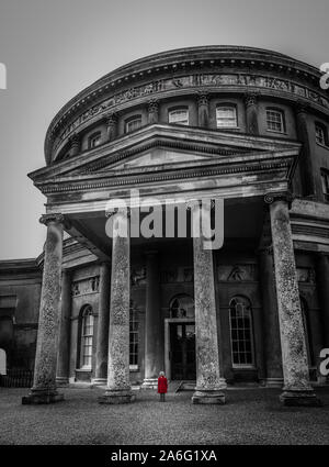 Une petite fille dans un manteau rouge à à Ickworth House sur une journée en famille, belle architecture et bâtiments historiques, isolé, seul, thoughful Banque D'Images