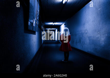 Spooky, image d'une petite fille portant un manteau rouge dans le couloir d'un bunker nucléaire secret, la sécurité, l'horreur, effrayant, d'isolement Banque D'Images