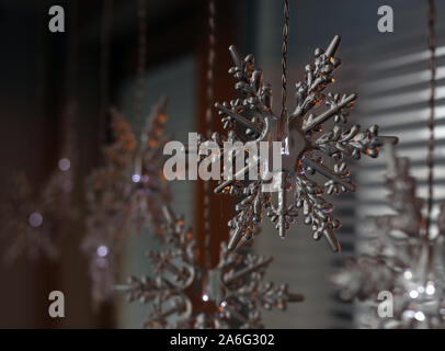 Lumières de Noël en forme de flocon de pendaison devant une fenêtre à l'intérieur. Belle pièce d'hiver / maison de vacances à thème de la saison la décoration de la maison. Banque D'Images