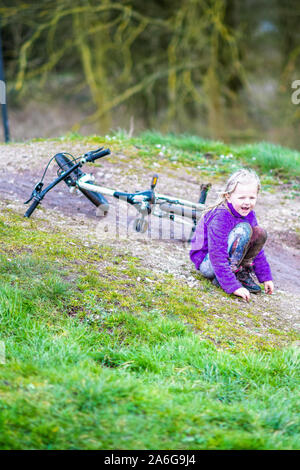 Une jolie petite fille aux cheveux blonds et un cavalier pourpre bénéficie d'une journée à la piste de BMX, équitation et la pratique de l'enfant, trucs et astuces dans la campagne UK Banque D'Images