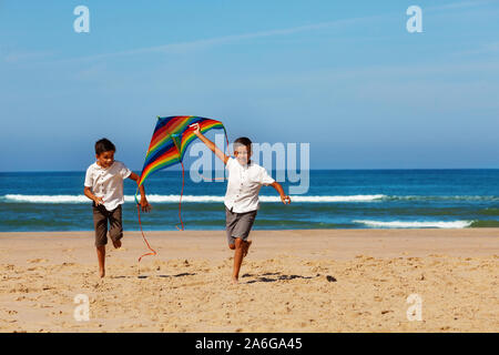 Deux garçons frères courir sur la plage avec kite Banque D'Images