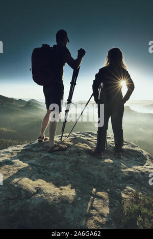 Deux photographes se retrouvent au lever du soleil ou à l'aube dans les montagnes. Fille avec de grands cheveux blonds guy slim parlent de la photographie. Banque D'Images