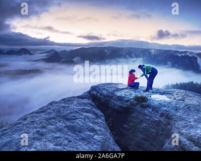 La nuit photo montre une femme la foudre Magique lanterne pour son homme. Femme assise sur un rocher et brille à l'obscurité brumeuse. Premiers rayons de soleil apparaissent dans l'étang du grand birieux Banque D'Images