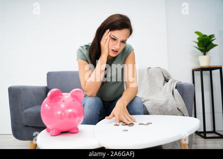 Jeune femme malheureuse de vider sa tirelire épargne avec moins que prévu à la maison Banque D'Images