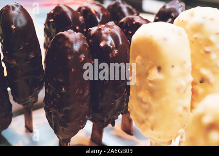 Ice cream on stick recouvert de chocolat sur fond flou. Banque D'Images