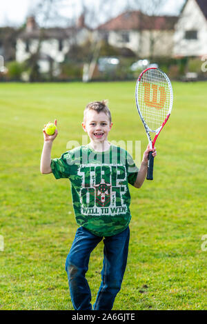 Un petit garçon avec le TDAH, l'Autisme, syndrome d'Aspergers aime jouer au tennis au parc et arrête de poser pour une photo Banque D'Images