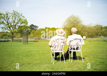 Un couple de personnes âgées d'hommes assis sur des chaises dans le bain de soleil sur la Walton, Essex  ? Banque D'Images