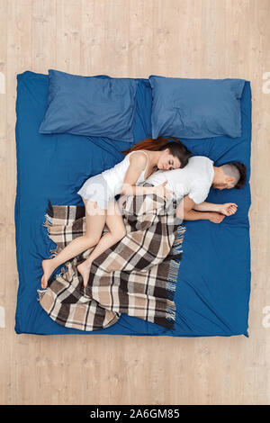 L'heure du coucher. Young woman hugging man sleeping on bed pacifique Vue de dessus Banque D'Images