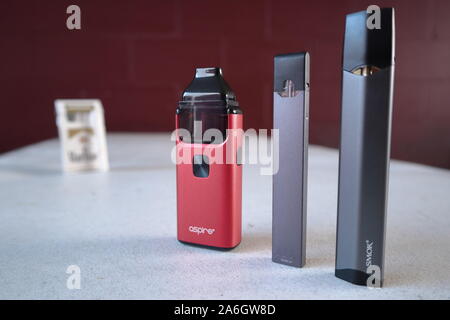 3 stylo vape différents dispositifs cigarette électronique juul, aspirent à la brise, smok infinix, avec un paquet de cigarettes Marlboro Gold dans l'arrière-plan de Banque D'Images